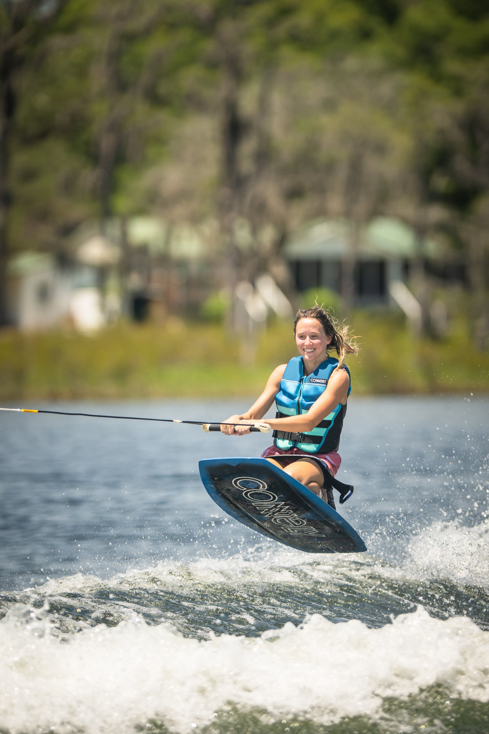 Rider in mid-air while kneeboarding on the Boost, gripping the handle and maintaining balance over the water‚Äôs wake.