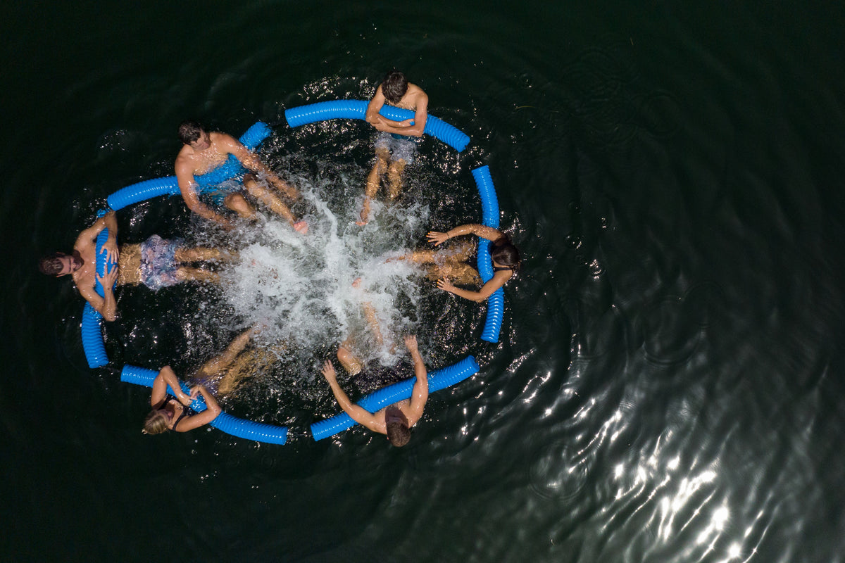 Group of people floating in a circle using the Party Noodle Connect on the water.