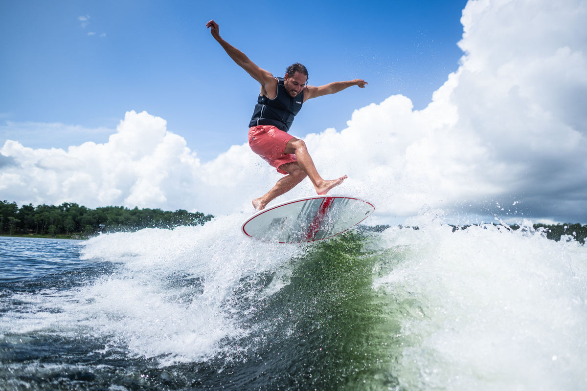 A rider catching air on the HABIT Skim wakesurf board, launching above the wave with arms outstretched.