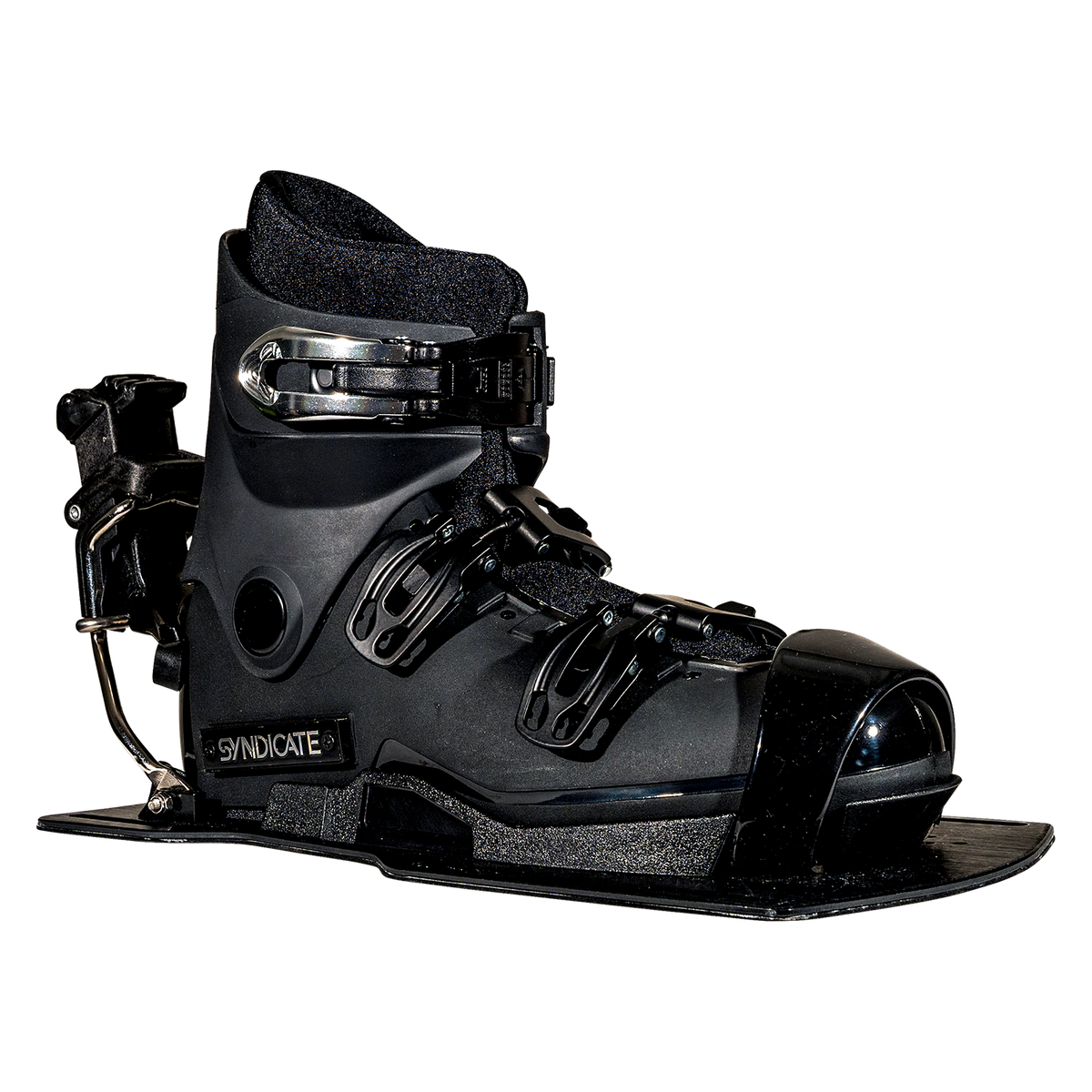 Angled front view of the Syndicate Hardshell boot, showing black construction, adjustable straps, and a metal heel release.