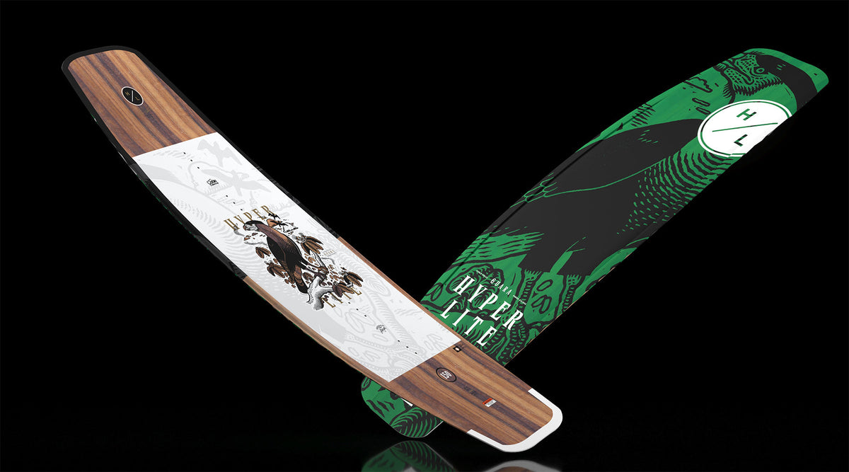 Angled view of Guara 153cm wakeboard with wood grain top and green bird graphic base.