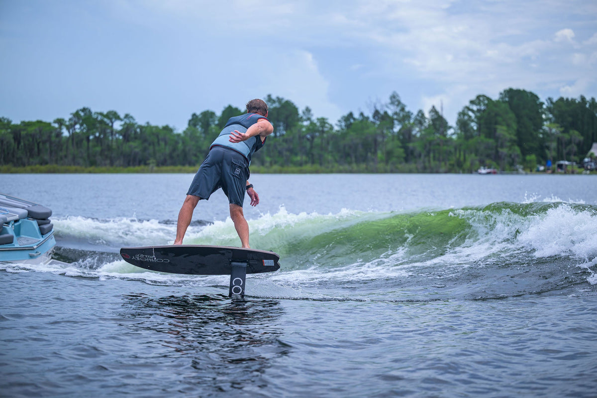Person wakefoiling on a lake with trees and sky in the background.