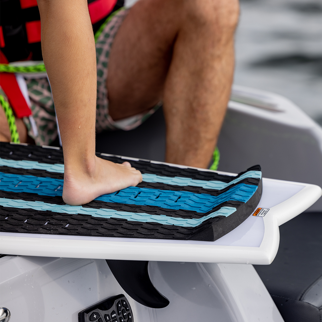 Close-up of a rider‚Äôs foot pressing against the Scout wakesurf board‚Äôs raised rear traction pad.