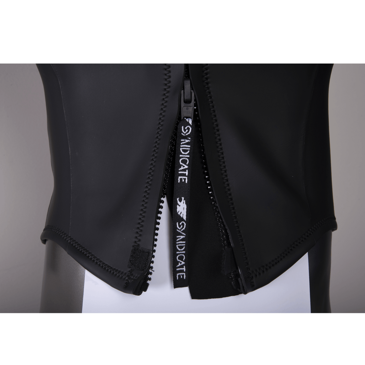 Close-up of the wetsuit zipper, showing the black Syndicate-branded pull tab and reinforced seams.